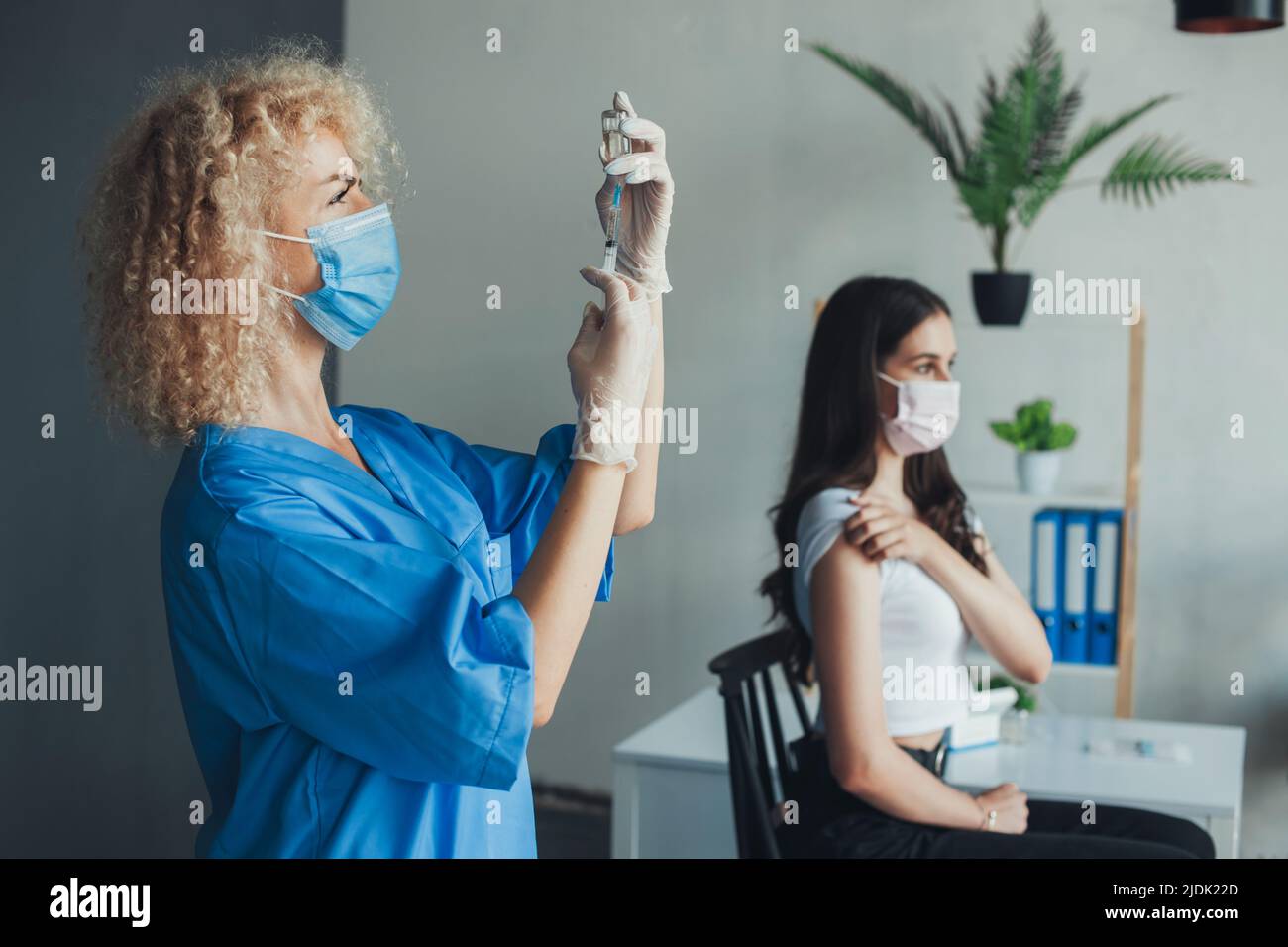 Femme médecin qui extrait une injection de vaccin Covid-19 avec une aiguille de seringue. Porter des gants et un masque à l'hôpital. Prévention des pandémies Banque D'Images