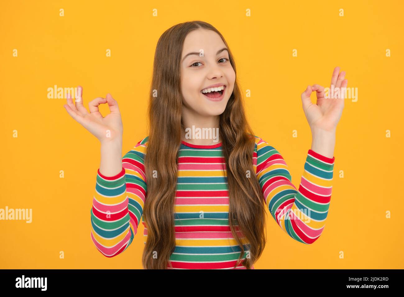 Jeune fille enfant montrer les doigts ok symbole langue signe isolé sur fond jaune. Drôle de visage d'adolescent. Banque D'Images