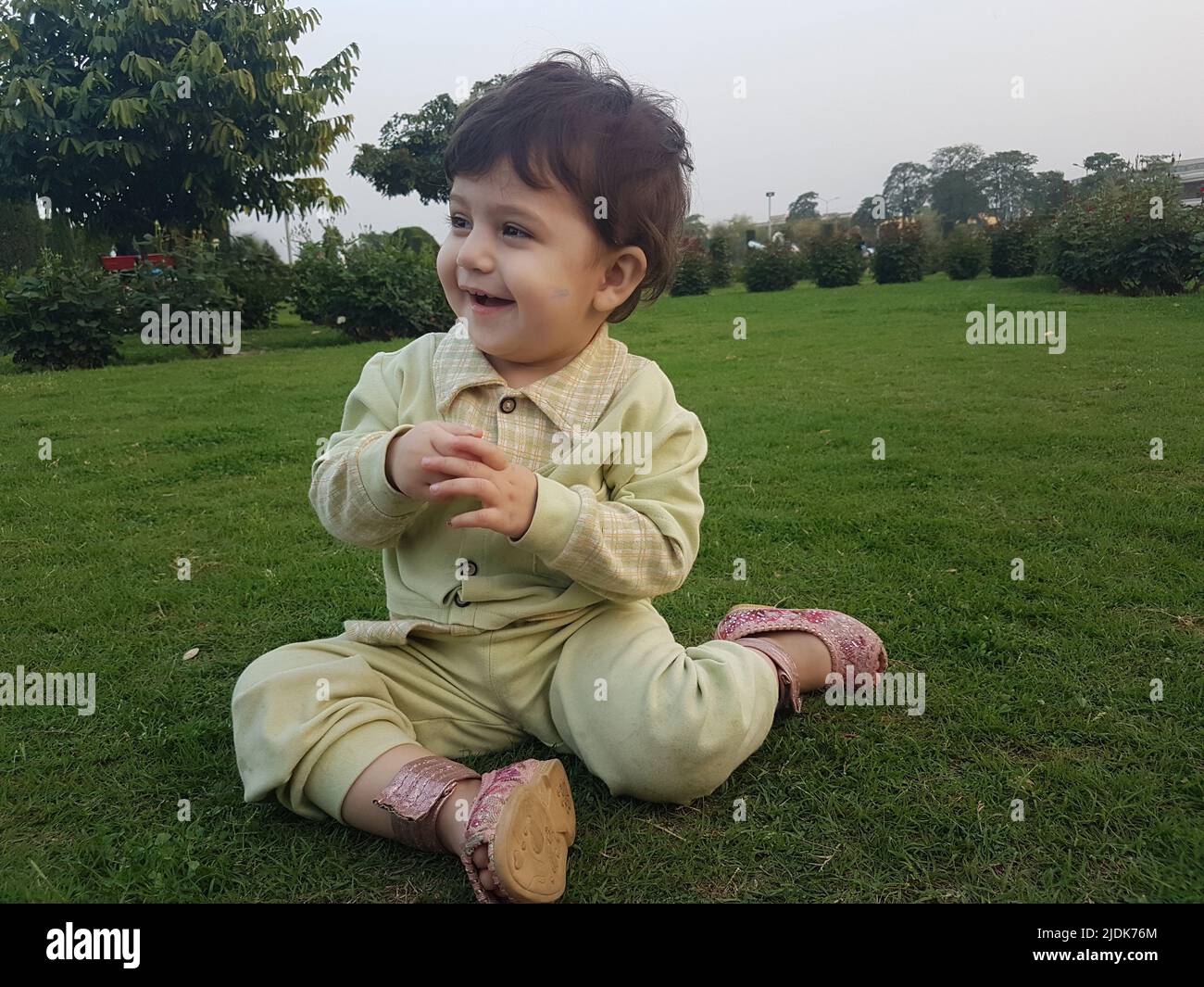 Petite fille mignonne avec un beau sourire assis dans un parc. Banque D'Images