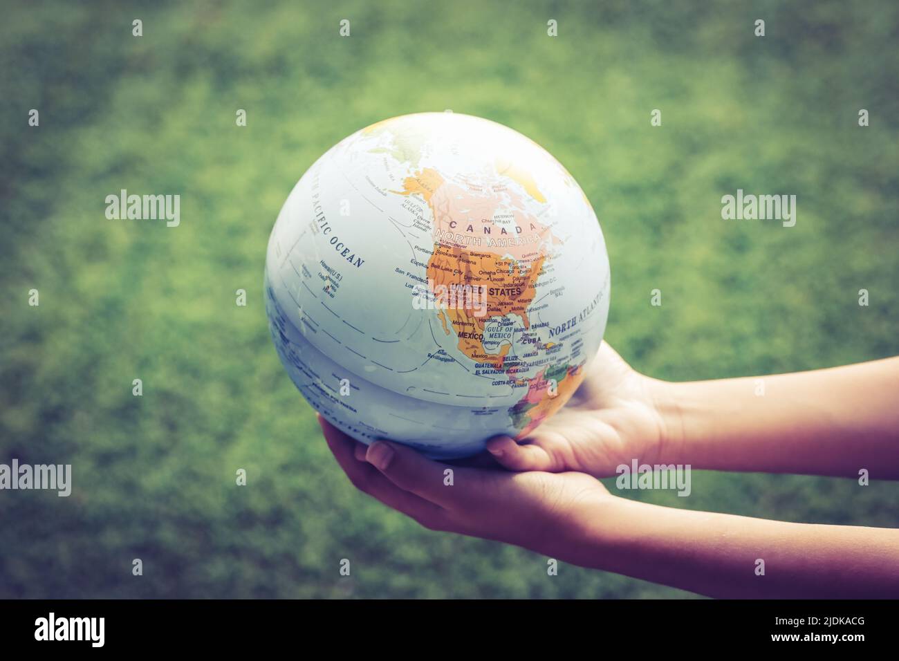 Un jeune garçon tenant un globe sur un terrain vert. Le concept de protection de la nature, de l'écologie et de la paix mondiale Banque D'Images