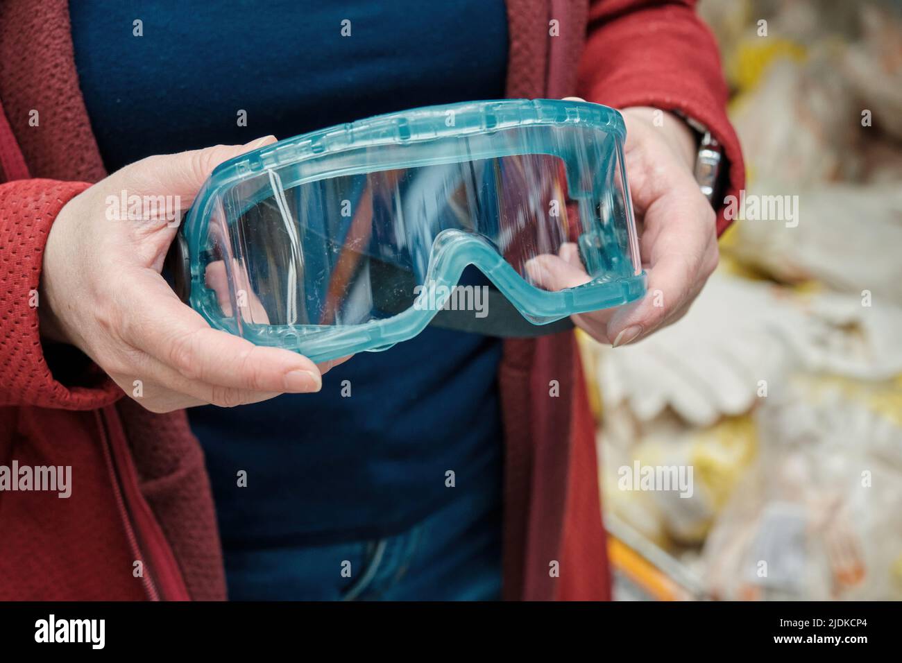 Femme dans le magasin de matériaux de construction choisit pour acheter des lunettes de protection en plastique Banque D'Images