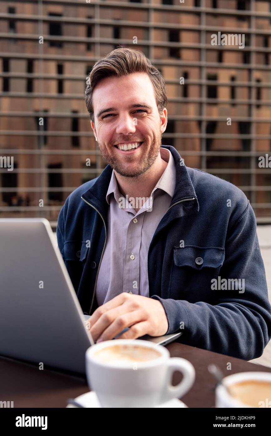 homme d'affaires souriant travaillant sur une terrasse Banque D'Images