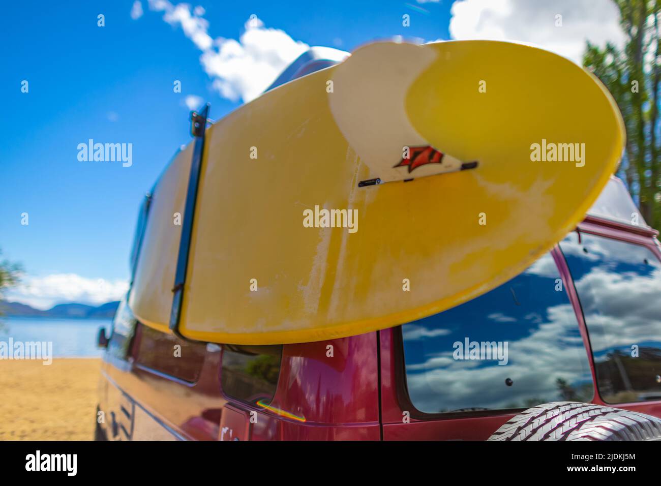 Fourgonnette avec surf coloré par une belle journée d'été. Voiture d'époque garée sur la plage ou en bord de mer avec une planche de surf Banque D'Images