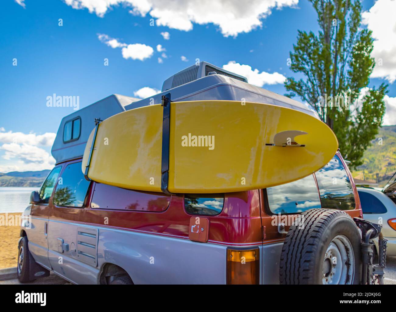 Fourgonnette avec surf coloré par une belle journée d'été. Voiture d'époque garée sur la plage ou en bord de mer avec une planche de surf Banque D'Images