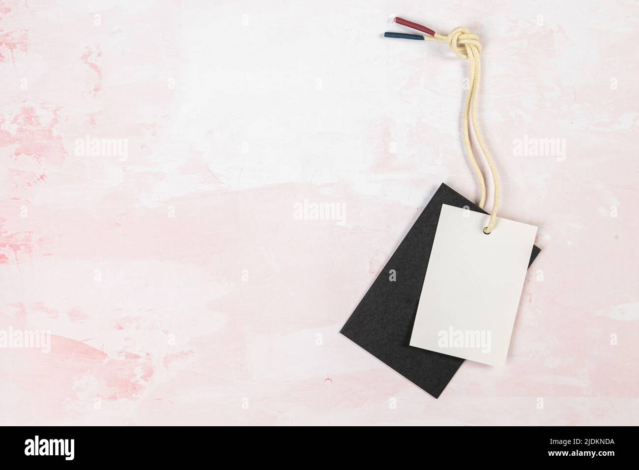 Étiquette de vêtement, modèle de maquette d'étiquette vierge sur une table rose Banque D'Images