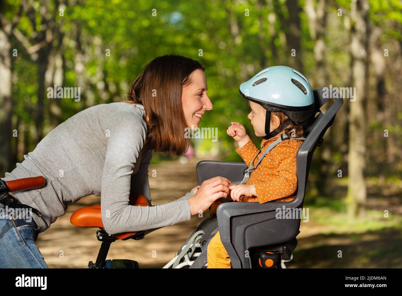 Une femme joue et parle avec une fille assise à vélo électrique Banque D'Images