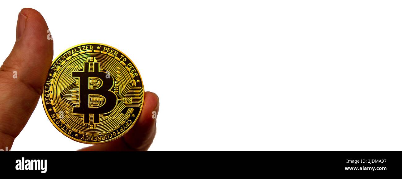 Deux doigts tiennent la pièce en métal doré d'un Bitcoin sur fond blanc Banque D'Images