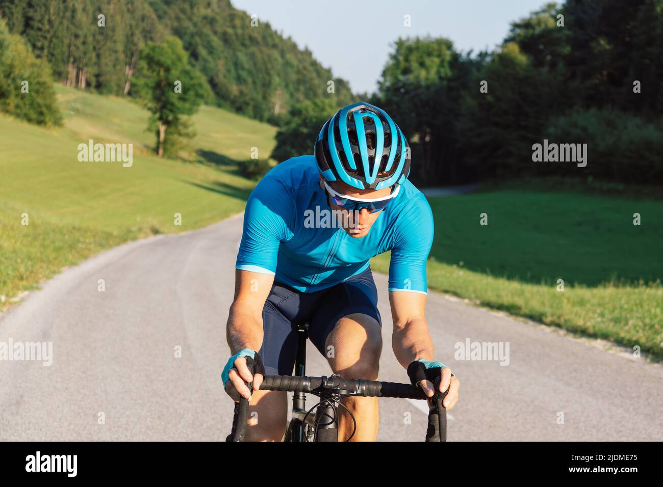 Coureur professionnel de vélo de route mâle prenant une position aérodynamique de corps pour le sprint sur un vélo, vue avant. Banque D'Images