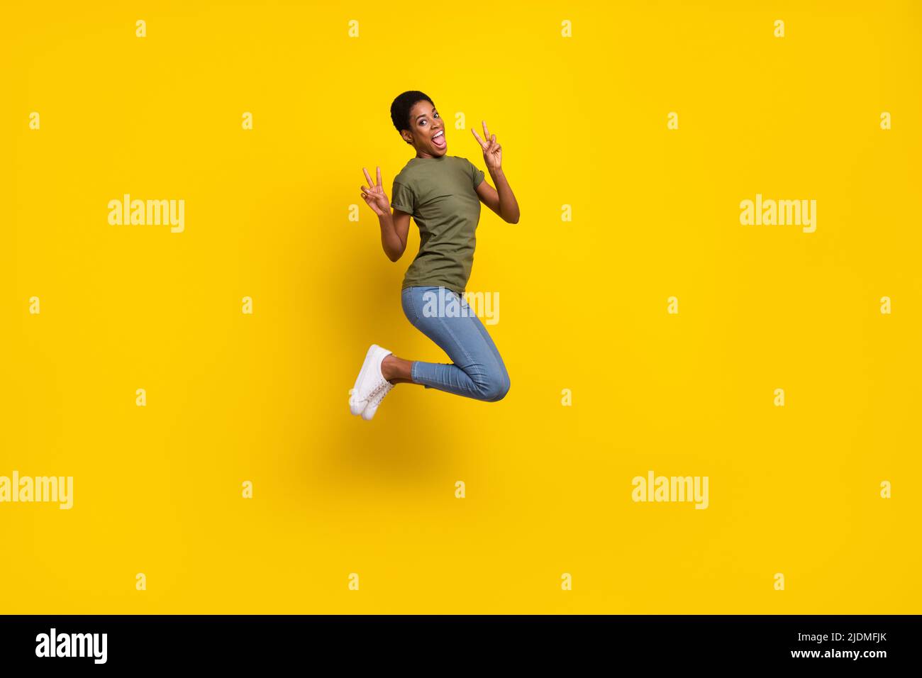 Portrait en longueur de la personne folle sympathique saut deux mains démontrent le V-signe isolé sur fond jaune de couleur Banque D'Images
