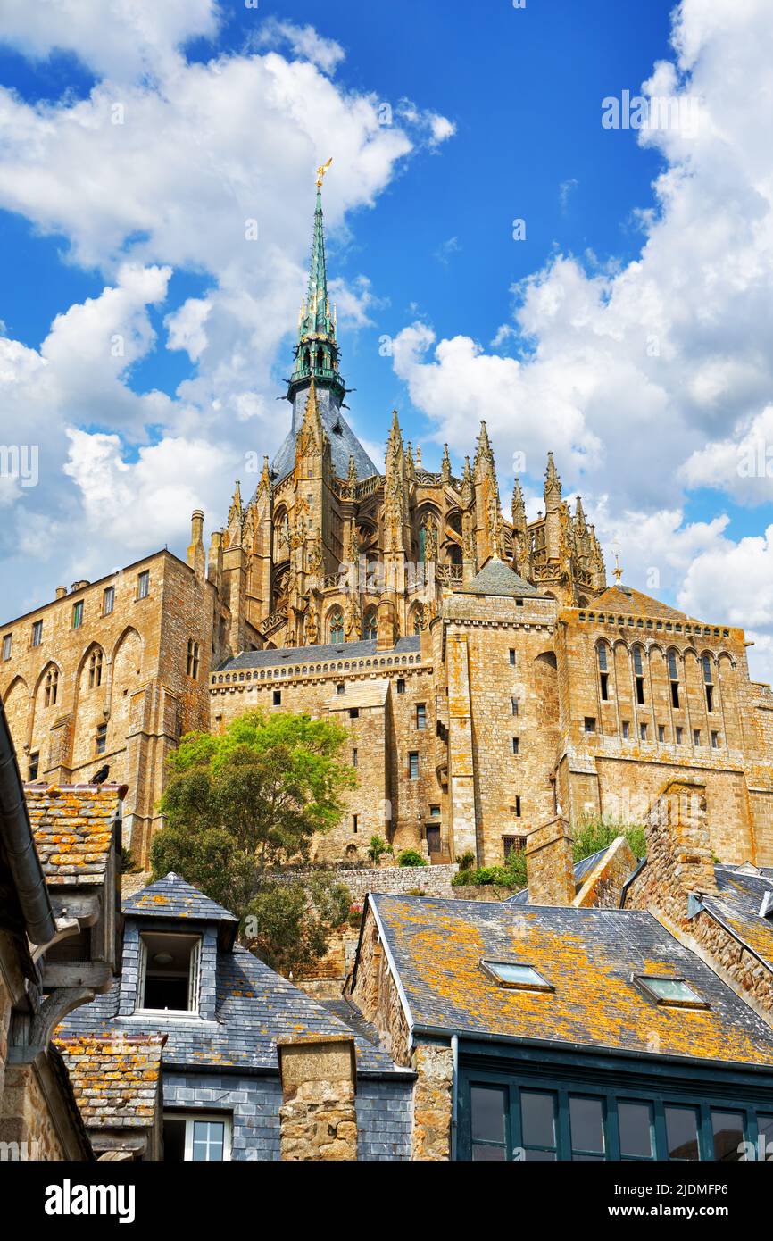 Les toits des maisons et les spiers de l'église de la ville du Mont Saint Michel contre le ciel bleu au soleil de midi. Mont-Saint-Michel, France Banque D'Images