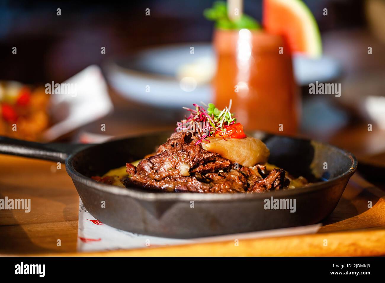 Viande fraîche cuite dans une poêle sur une table en bois dans un restaurant de luxe. Beaf grillée avec légumes et boisson froide sur fond. Cuisine fine Banque D'Images