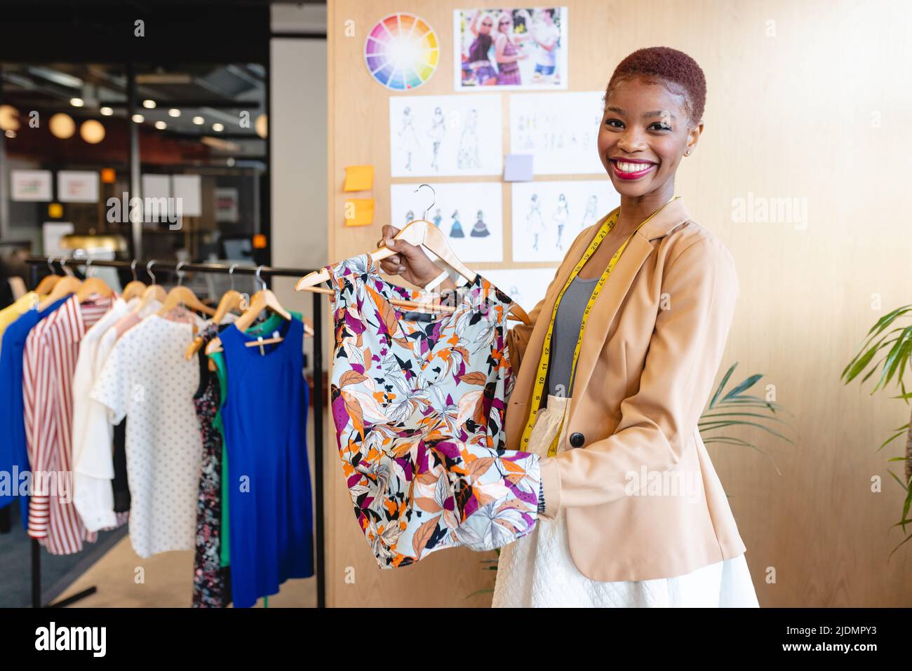 Portrait d'une couturier afro-américaine souriante montrant un vêtement à motifs au bureau Banque D'Images