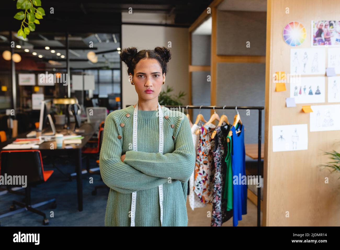 Portrait d'une femme de mode biracial confiante debout avec les bras croisés en studio Banque D'Images