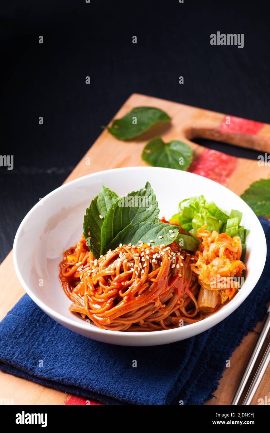 Food concept korean Spice Cold sarrasin Noodle Kimchi Bibim Guksu sur bois et fond noir avec espace de copie Banque D'Images