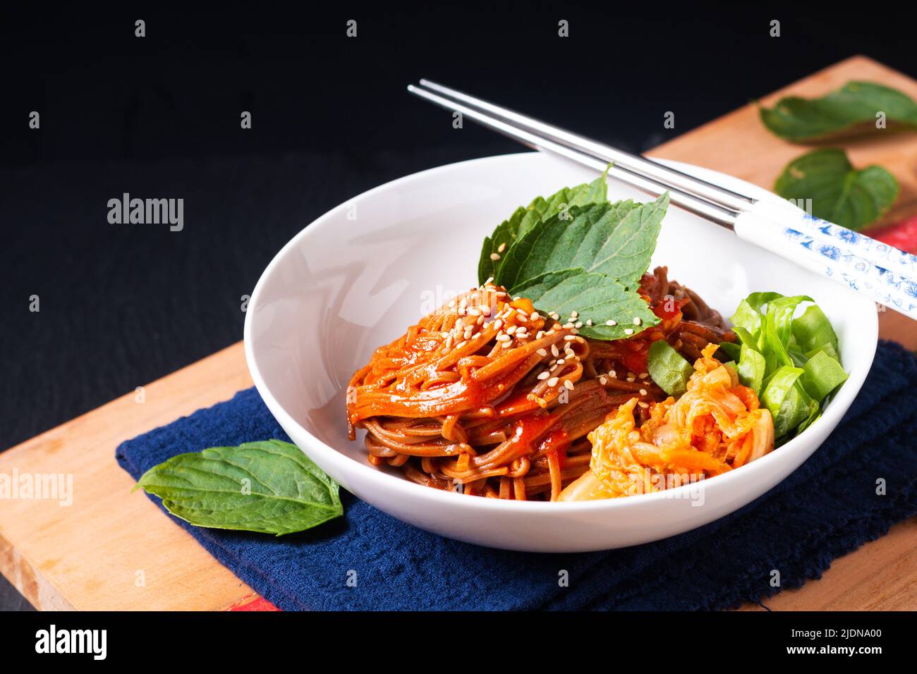 Food concept korean Spice Cold sarrasin Noodle Kimchi Bibim Guksu sur bois et fond noir avec espace de copie Banque D'Images