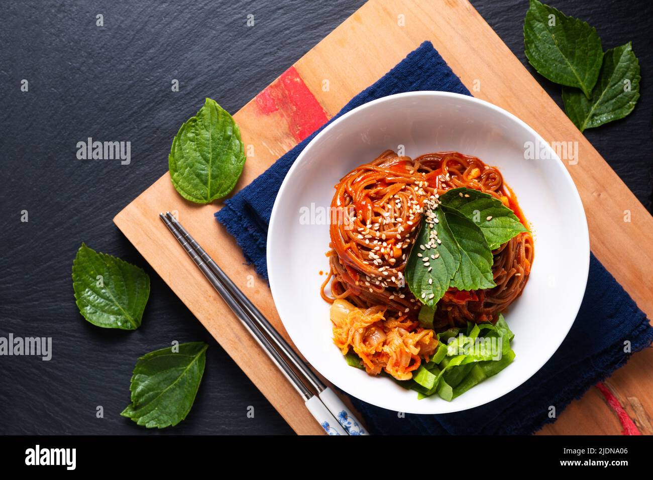 Food concept korean Spice Cold sarrasin Noodle Kimchi Bibim Guksu sur bois et fond noir avec espace de copie Banque D'Images