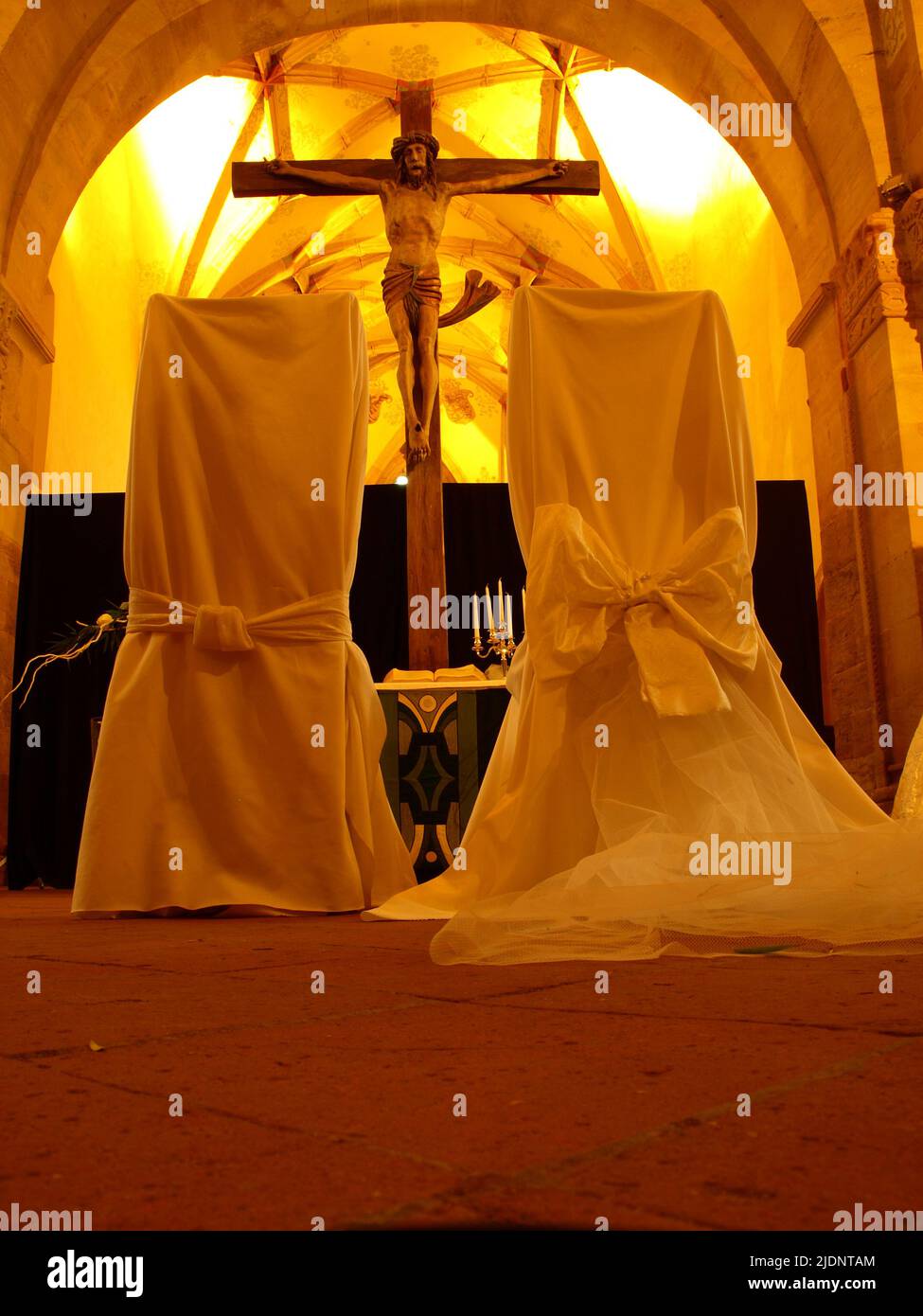 Préparation du mariage. Deux chaises de mariage face à l'autel éclairé avec une croix au milieu. Banque D'Images