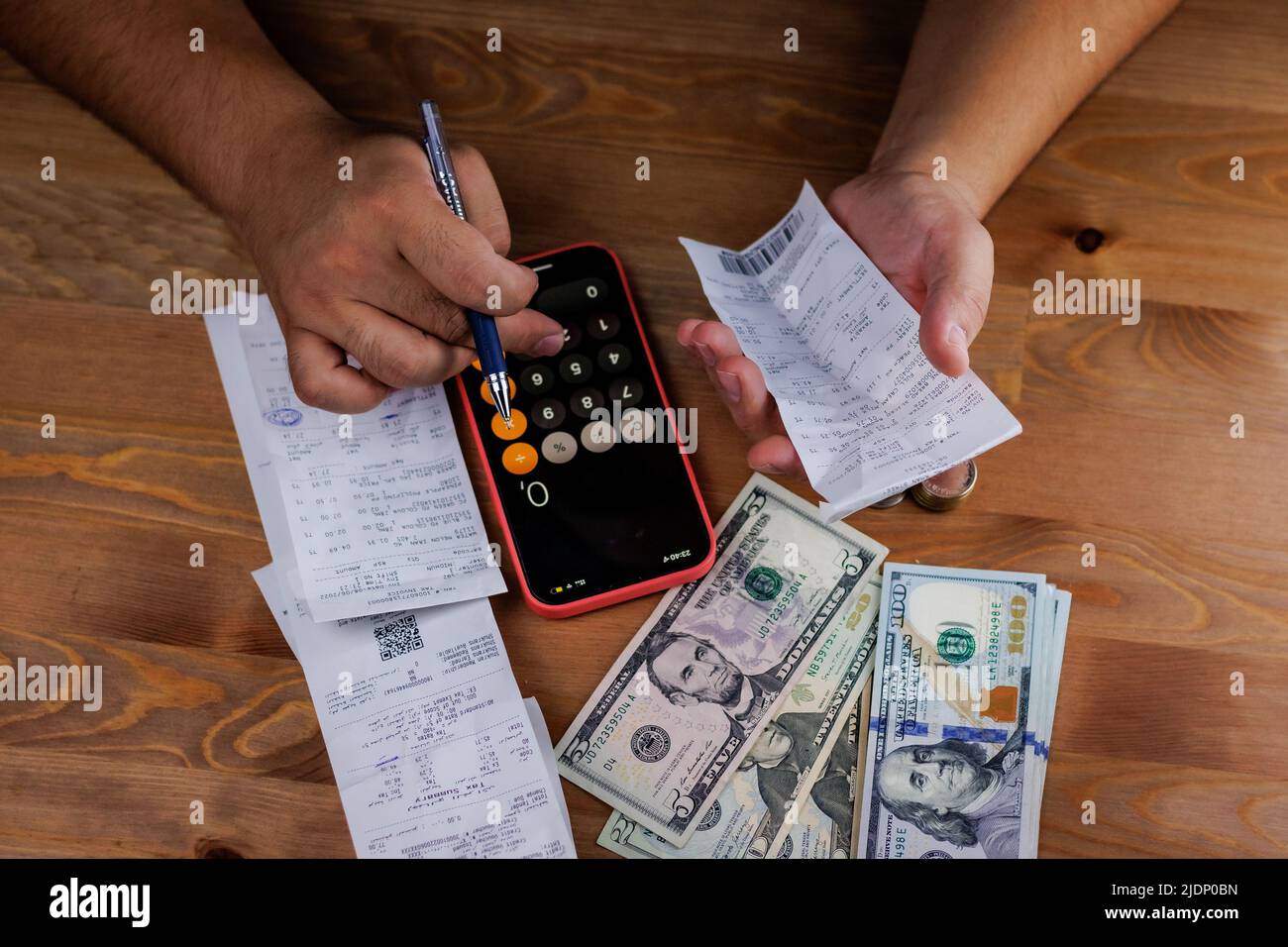 chèques sur la table avec de l'argent, un homme compte ses dépenses sur une calculatrice Banque D'Images