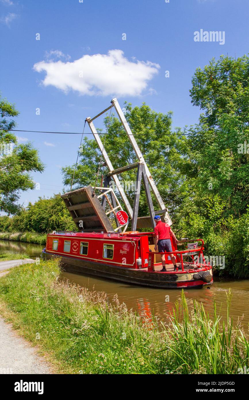 Un homme dirige un bateau étroit de canal à travers le pont levant de Morris sur le canal Llangollen à Whixall Moss près de Whitchurch England Banque D'Images