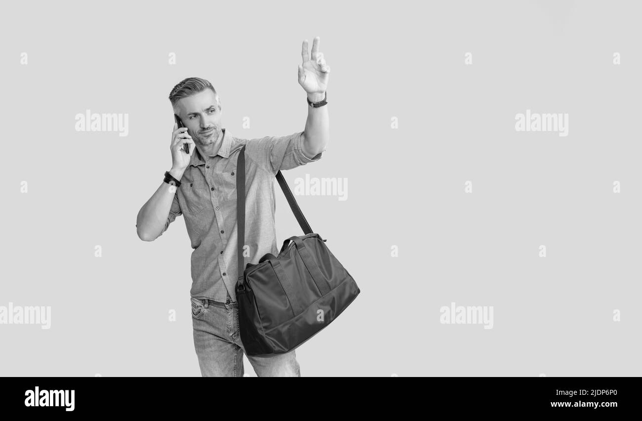 homme parlant sur un smartphone avec un sac de voyage en faisant un bonjour sur fond jaune, un espace de copie, la paix Banque D'Images