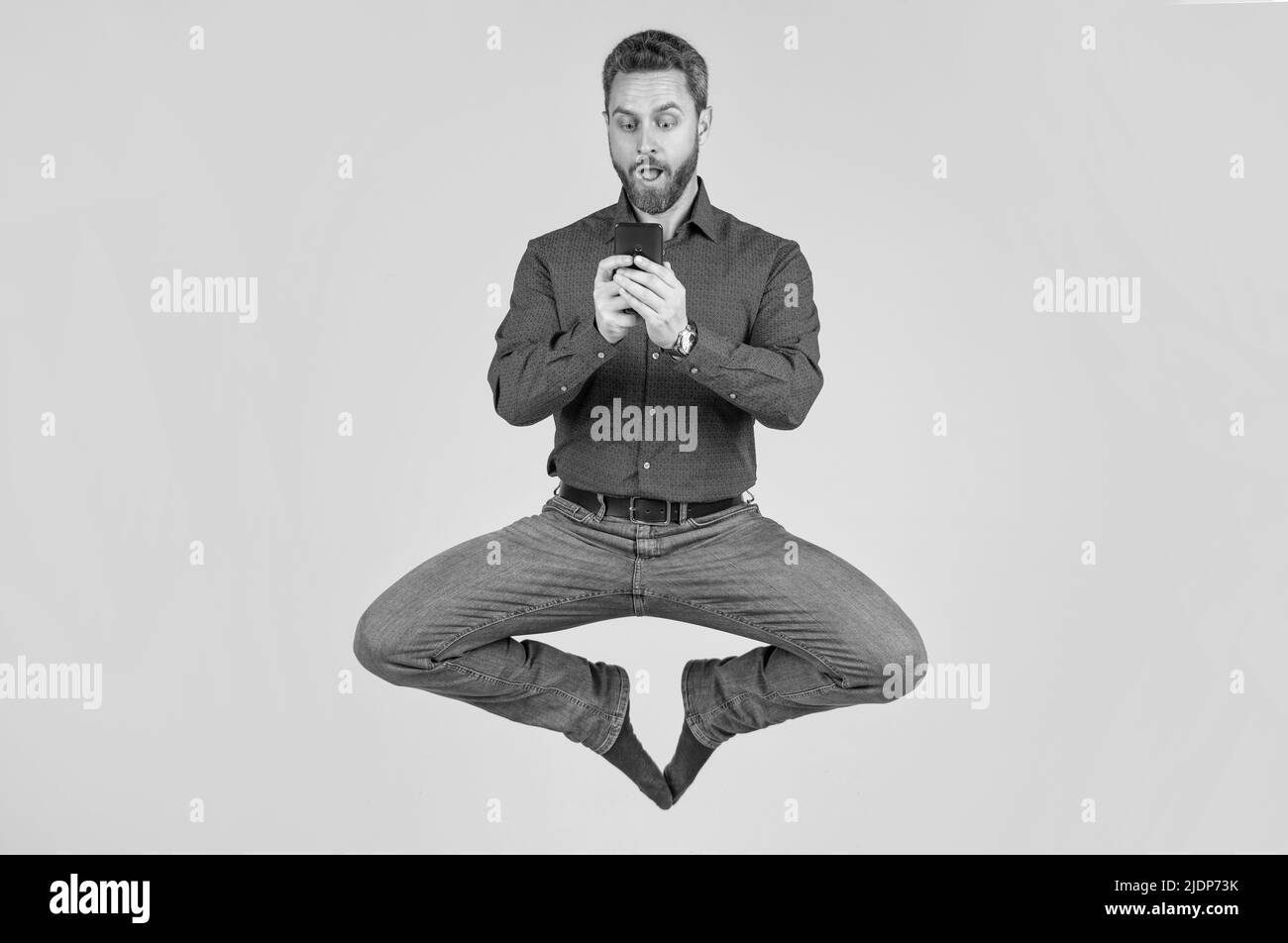 saut homme homme homme homme homme homme d'affaires bavardant en ligne sur smartphone et méditant dans la pose de yoga, le yoga d'affaires. Banque D'Images