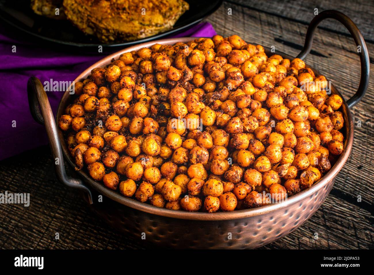 Pois chiches rôtis au sumac et aux épices : haricots de jarbanzo rôtis servis dans un plat de balti en cuivre martelé Banque D'Images