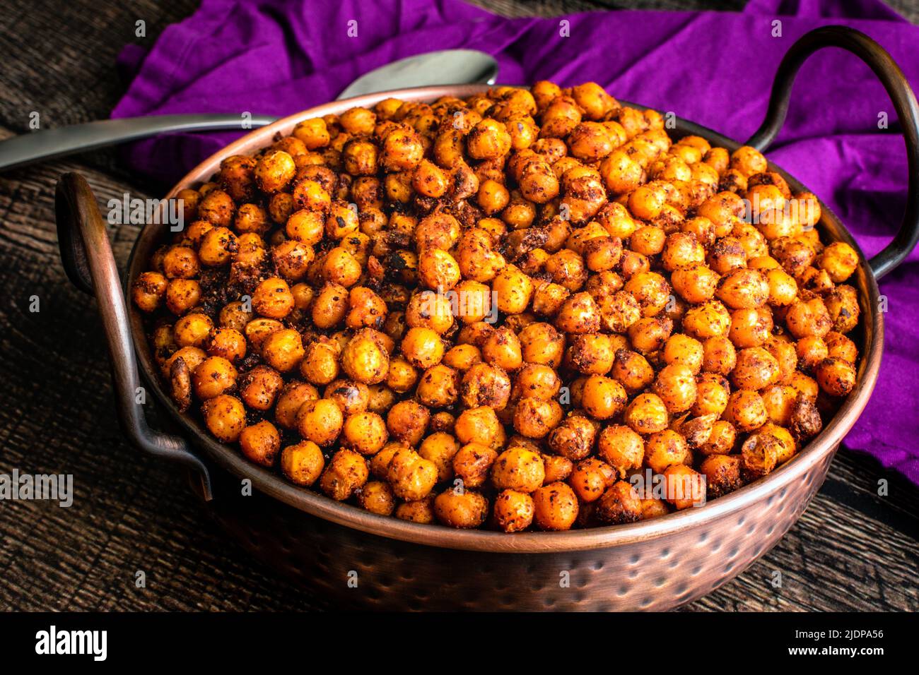 Pois chiches rôtis au sumac et aux épices : haricots de jarbanzo rôtis servis dans un plat de balti en cuivre martelé Banque D'Images