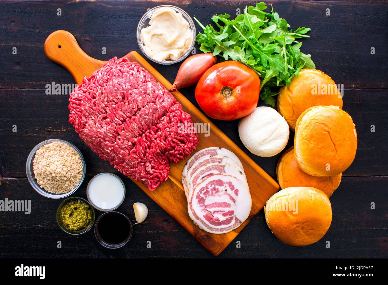 Ingrédients bruts du hamburger Tuscano sur un fond de bois foncé : bœuf haché, fromage mozzarella frais, pancetta et autres ingrédients de hamburger non cuits Banque D'Images