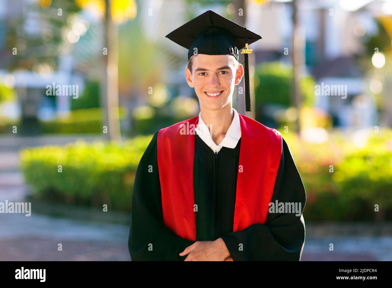 Cérémonie de remise des diplômes à l'école ou à l'université. Jeune homme en régalia académique, robe et Cap, certificat de célébration réussi de diplôme. Banque D'Images