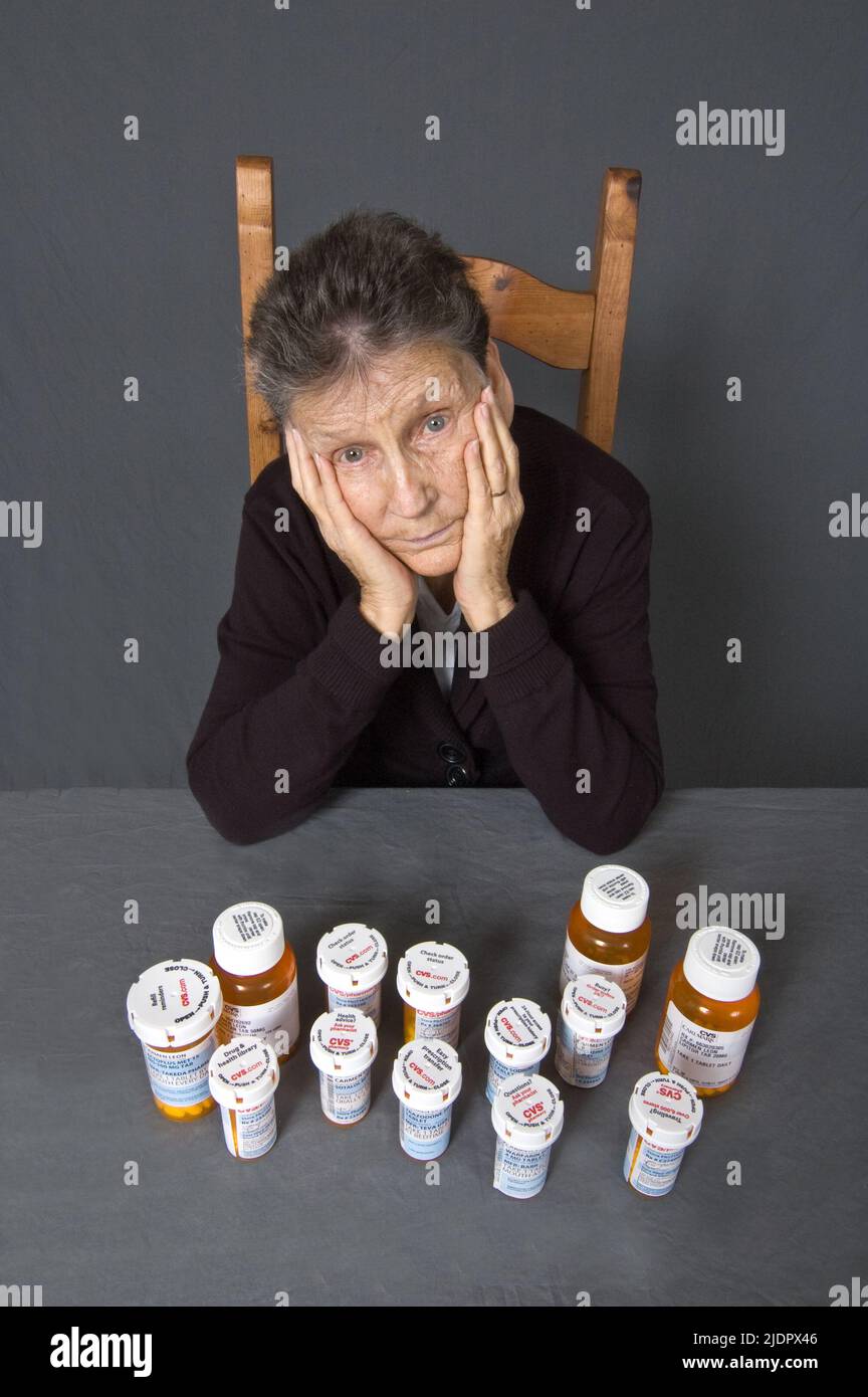 Une femme de 85 ans, latina assise devant tous les médicaments qu'elle prend pour ses diverses affections. Banque D'Images
