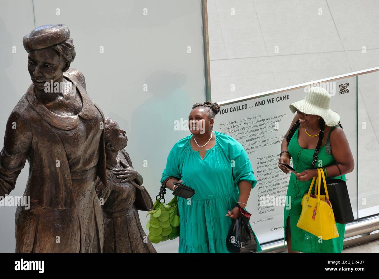 Londres, Royaume-Uni, 22nd juin 2022. Deux femmes regardent de plus près la statue de Windrush conçue par le sculpteur jamaïcain Basil Watson et dévoilée à la gare de Waterloo le jour de Windrush, célébrant les pionniers arrivés aux docks de Tilbury en 1948 et ceux qui ont suivi, jusqu'en 1971. Les trois figures - représentant un homme, une femme et un enfant debout sur des valises symbolise le lien de la génération Windrush. Crédit : onzième heure Photographie/Alamy Live News Banque D'Images