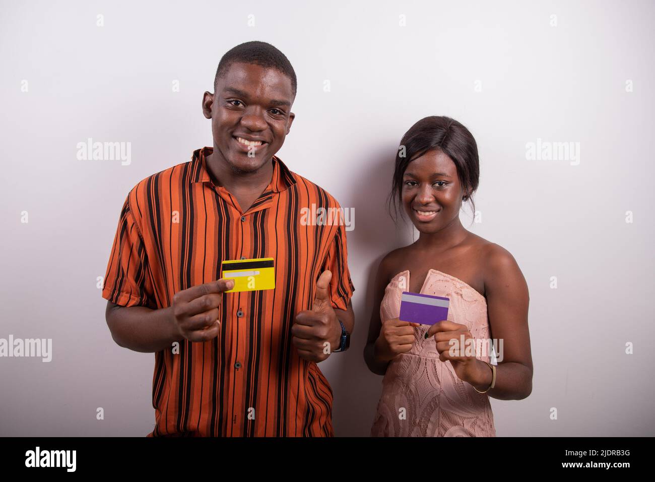 Un couple africain détient deux cartes de crédit et ils sourient, ils encouragent les paiements électroniques en Afrique Banque D'Images