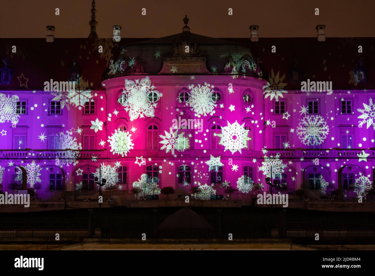 Varsovie, Pologne, façade du château royal illuminée la nuit avec des flocons de neige tombant pendant la période des fêtes de Noël en hiver. Banque D'Images