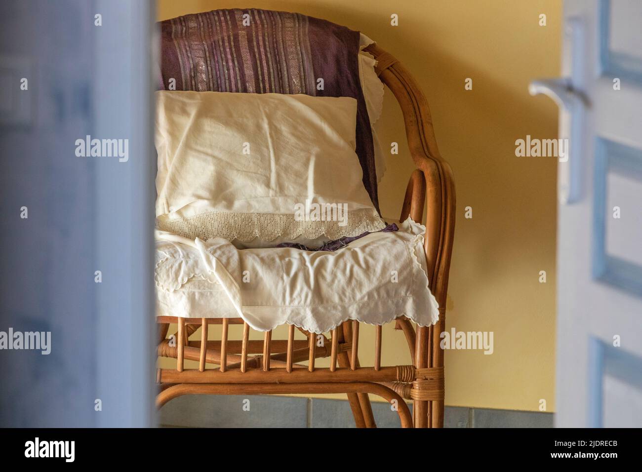 Une chaise de chambre en osier avec un coussin et du matériel dessus Banque D'Images