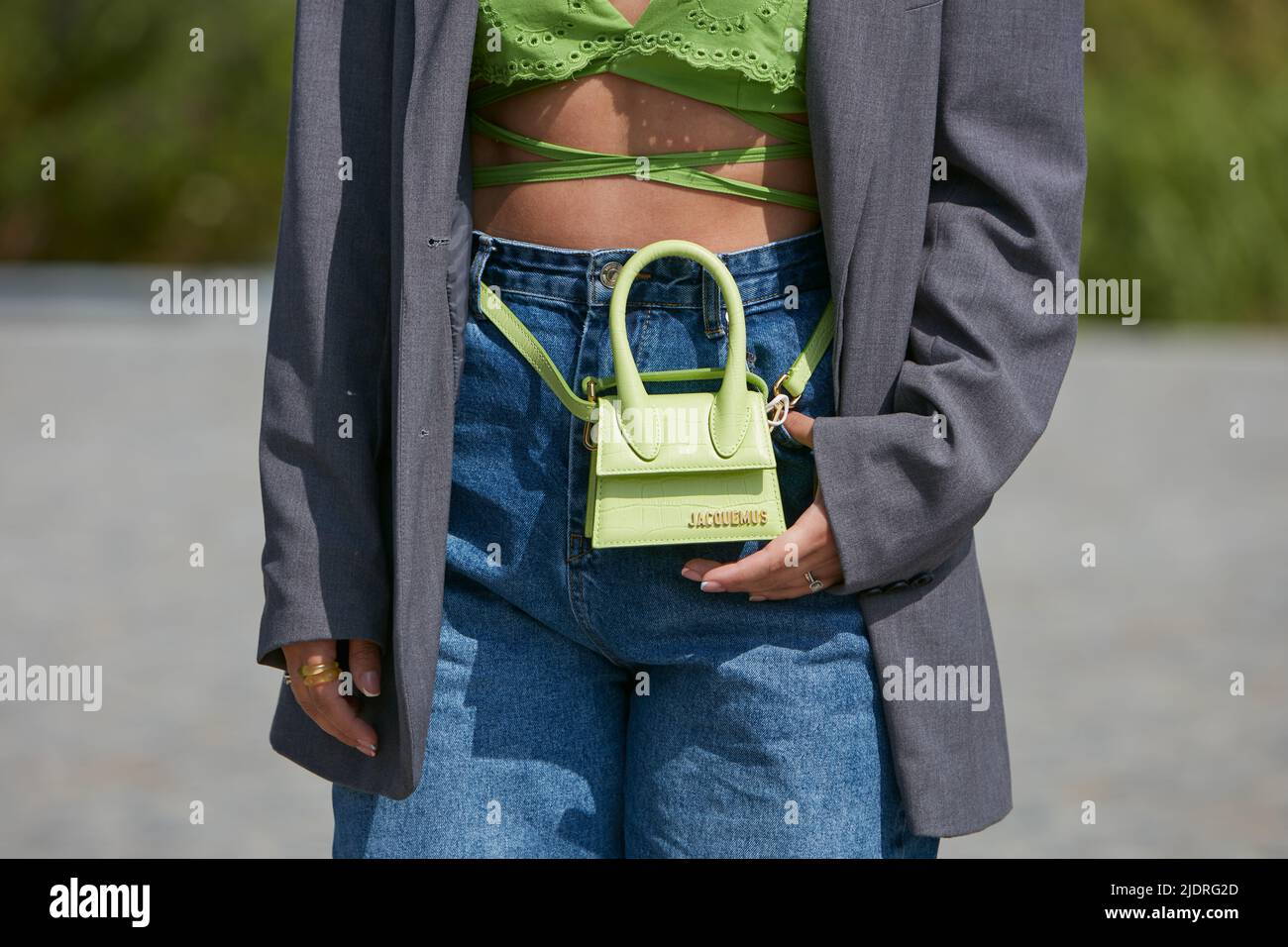 MILAN, ITALIE - 18 JUIN 2022 : femme avec un petit sac en cuir Jacquemus vert et un pantalon en denim bleu avant le salon de la mode MSGM, la tenue de la semaine de la mode de Milan Banque D'Images