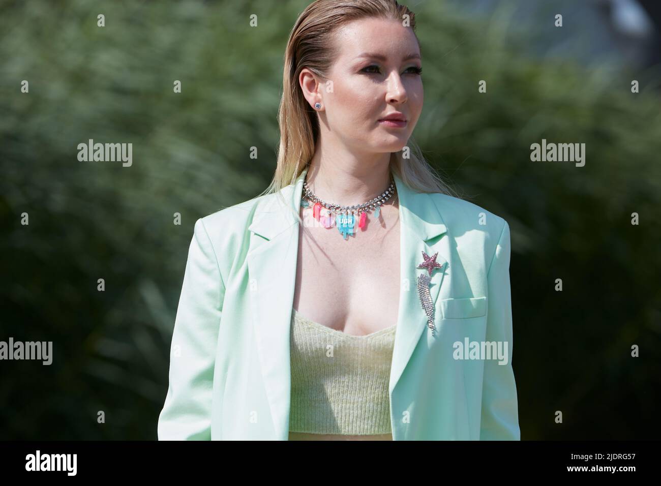 MILAN, ITALIE - 18 JUIN 2022 : femme avec veste turquoise et collier avec objets bleus et roses avant le spectacle de mode MSGM, rue de la semaine de la mode de Milan Banque D'Images