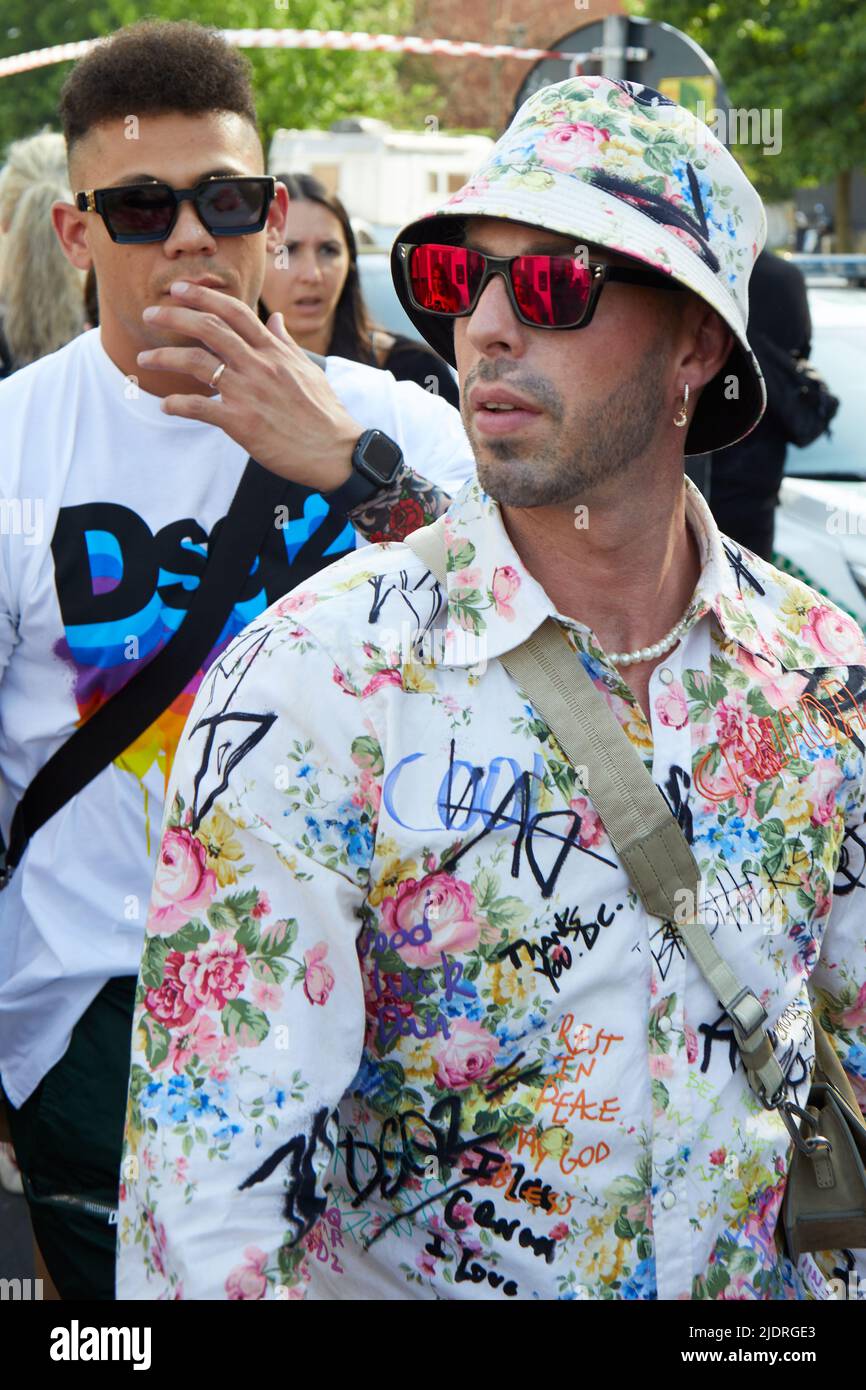 MILAN, ITALIE - 17 JUIN 2022: Homme avec chemise et chapeau fleuris et verres rouges lunettes de soleil avant Dsquared2 défilé de mode, Milan Fashion week Street style Banque D'Images