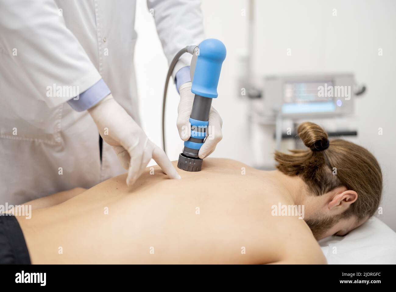 Le médecin applique un traitement par onde de choc sur l'épaule des hommes Banque D'Images