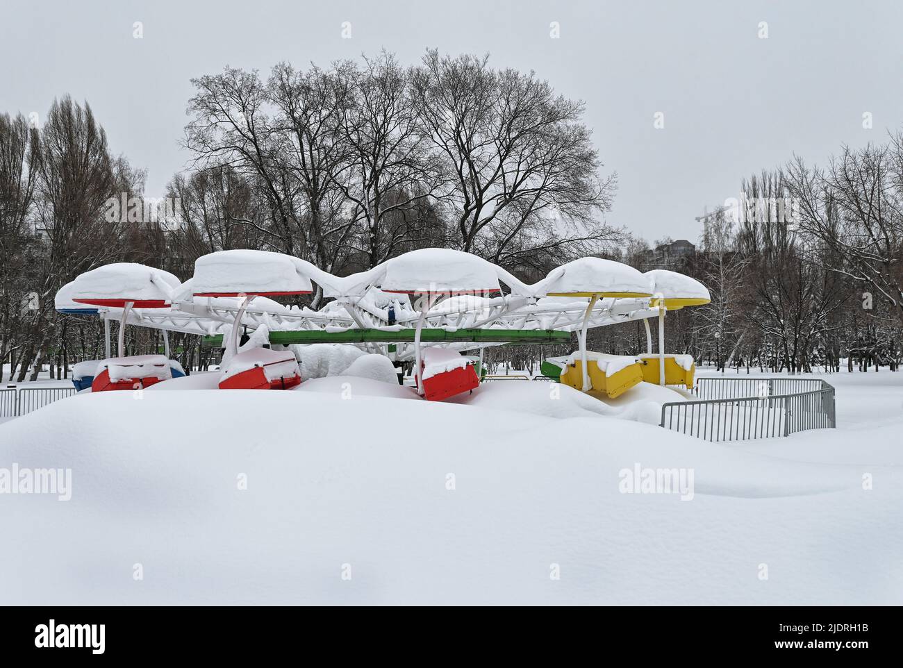 Vieux carrousel couvert de neige dans un parc urbain enneigé le jour d'hiver sombre Banque D'Images