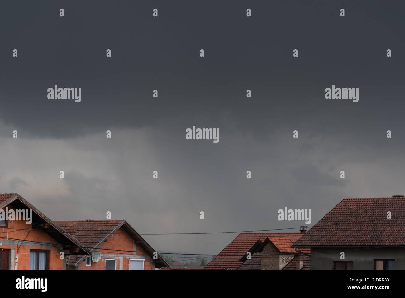 Des nuages sombres planaient sur les toits avec des précipitations, des nuages de tempête dans la banlieue Banque D'Images