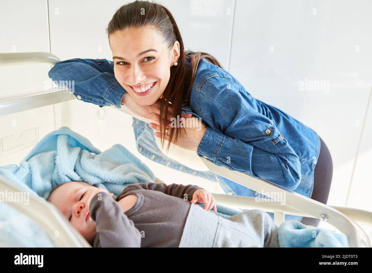 Mère souriante et fière au lit bébé pour l'amour de la mère et la maternité Banque D'Images