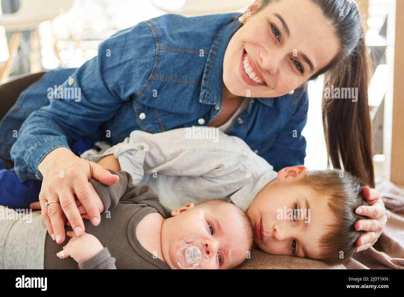 Mère heureuse et fière avec bébé et enfant sur le canapé dans le salon Banque D'Images