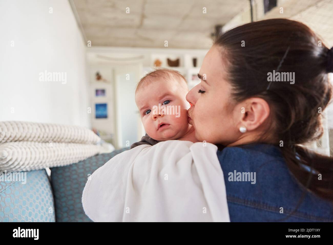 Mère donne à son bébé un baiser tendre sur la joue à la maison dans le salon Banque D'Images