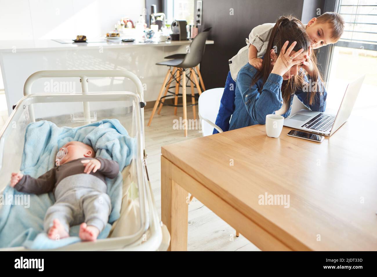 Mère seule avec l'épuisement dans le bureau à la maison avec bébé et enfant devant l'ordinateur portable Banque D'Images