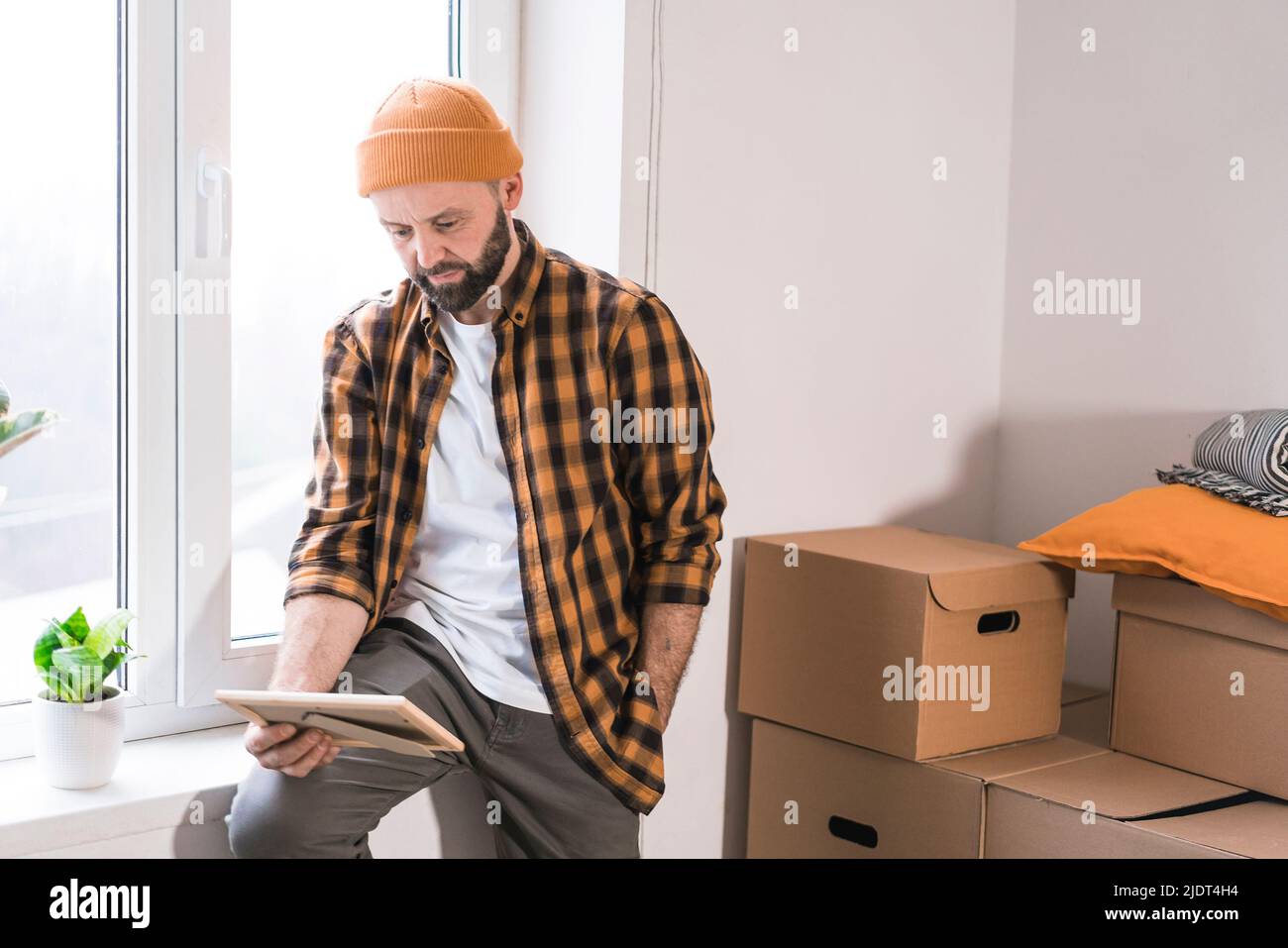 Hipster homme avec des boîtes mobiles dans nouvel appartement moderne. Homme mûr déballant des objets des boîtes tout en déplaçant dans un nouvel appartement. Banque D'Images
