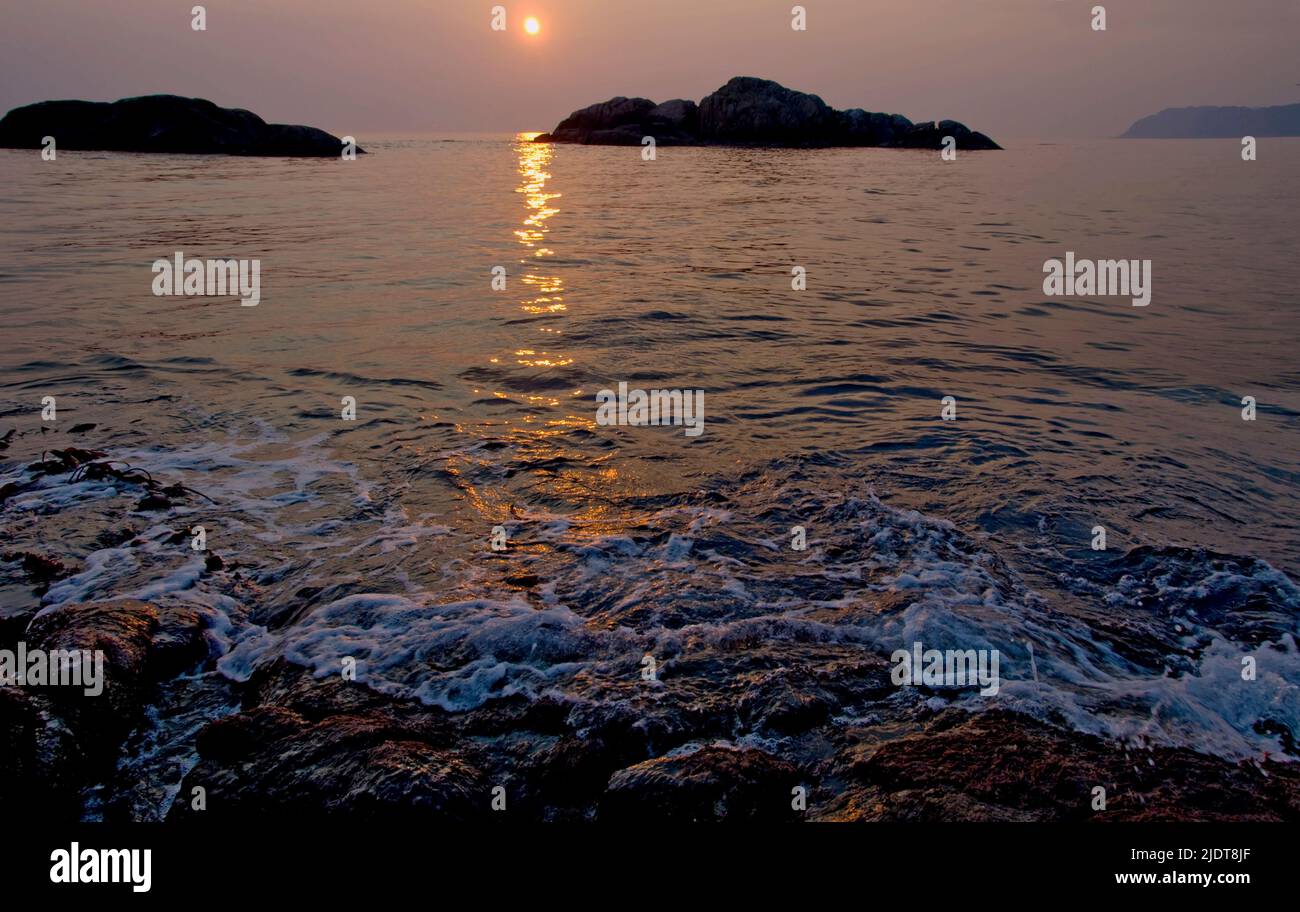 Le soleil d'avril se couche dans la mer du Nord à l'ouest de la petite île de Hidra, près de la pointe sud de la Norvège. Banque D'Images