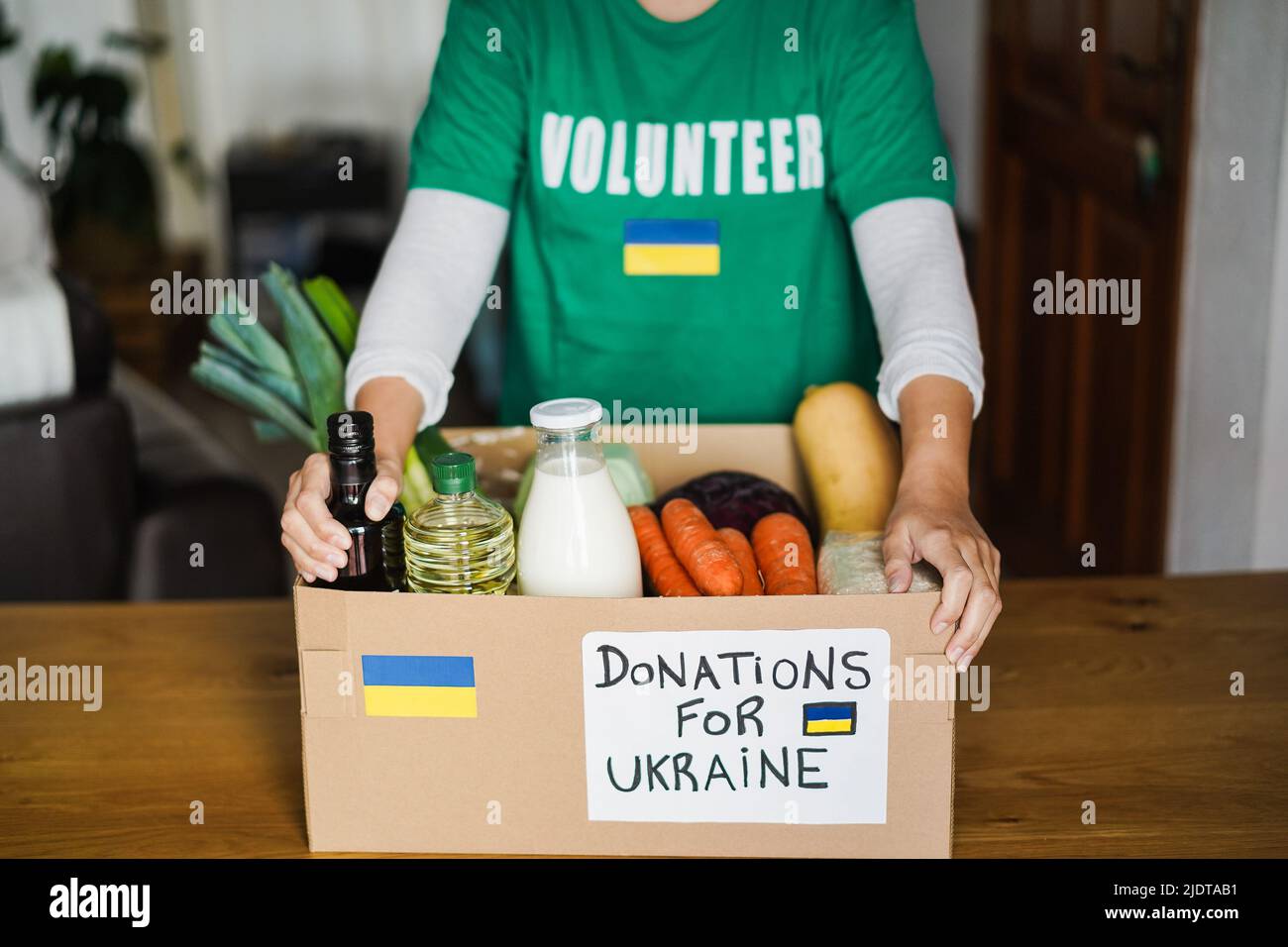 Volontaire préparant une boîte alimentaire pour les réfugiés de guerre d'Ukraine - Focus sur les mains tenant la boîte Banque D'Images