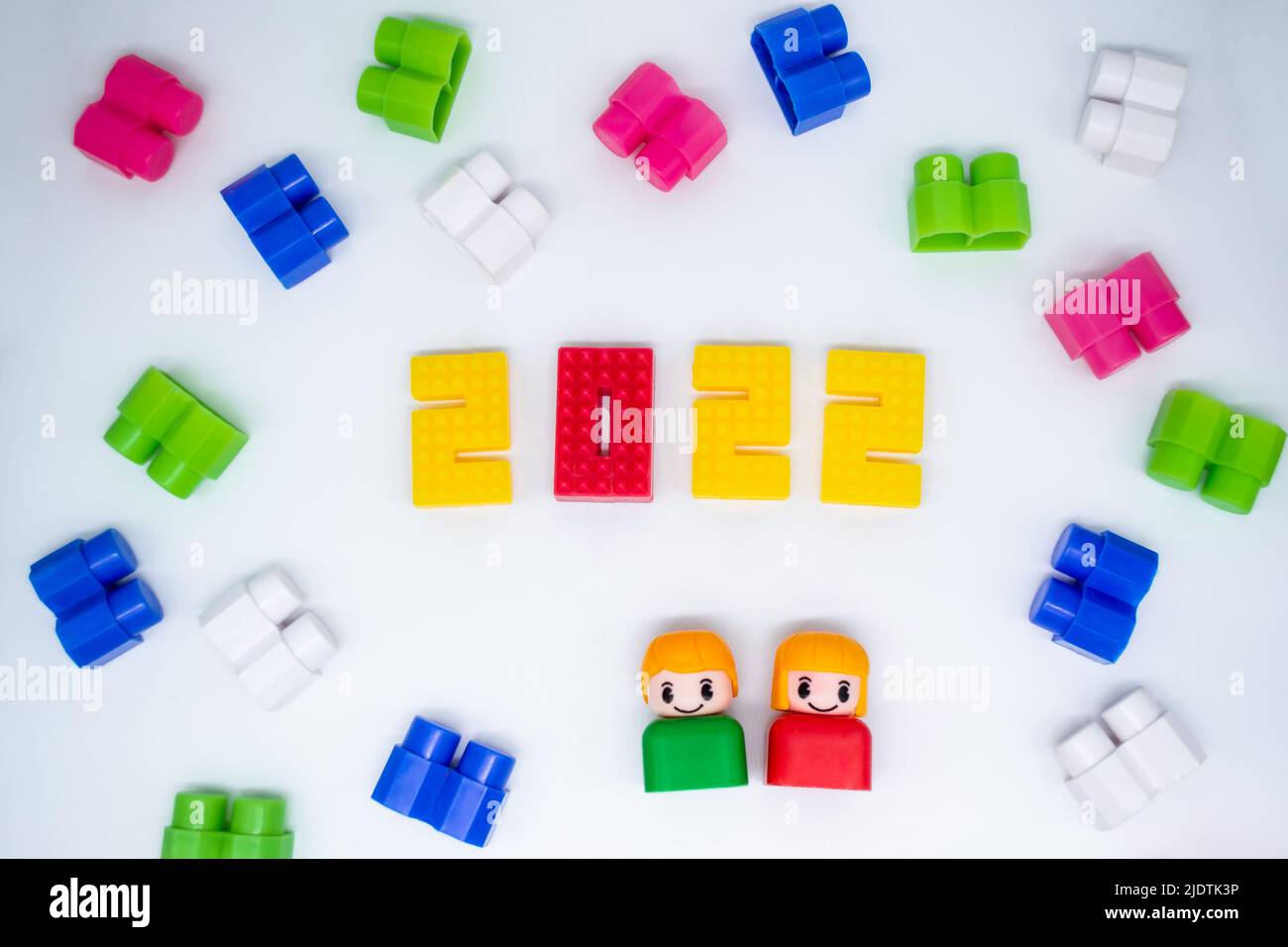 Blocs de construction colorés, jouets figures en plastique: Fille en 2022 chiffres et garçon vert sur fond blanc. Banque D'Images