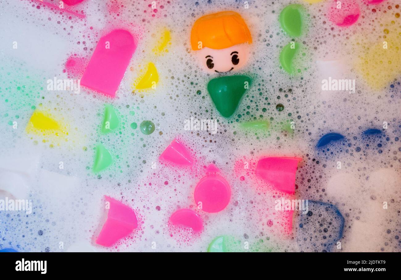 Lavage de jouets pour enfants, blocs de construction en plastique avec figurines. Un petit ami souriant et des cubes colorés flottent dans l'eau mousseuse. Le concept o Banque D'Images