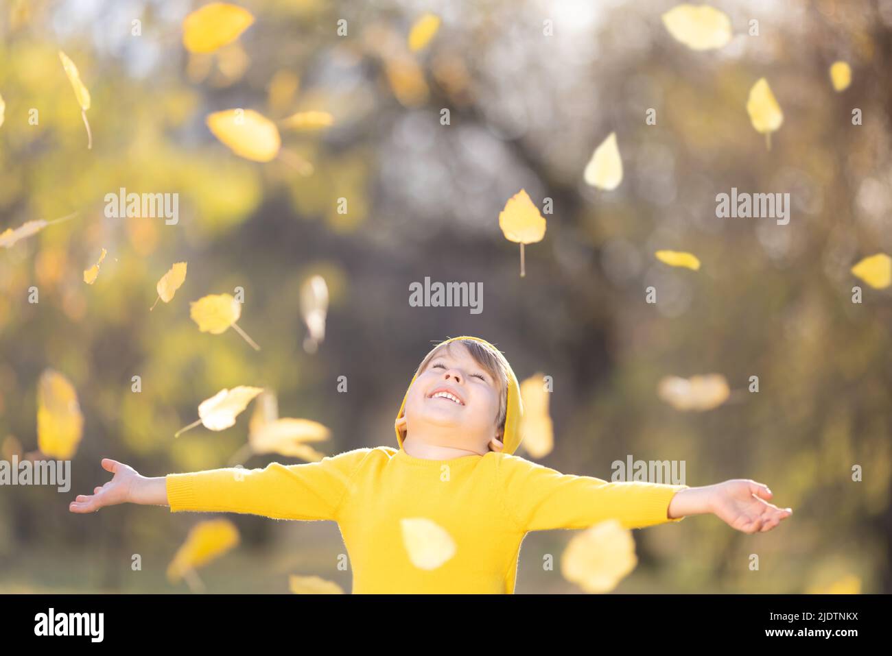 Un enfant heureux jette des feuilles jaunes. Enfant souriant s'amuser en plein air dans le parc d'automne. Concept de liberté et d'imagination Banque D'Images